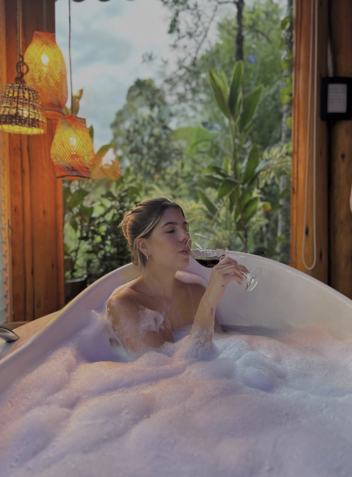 Banheira de hidromassagem com espuma e vista para a mata