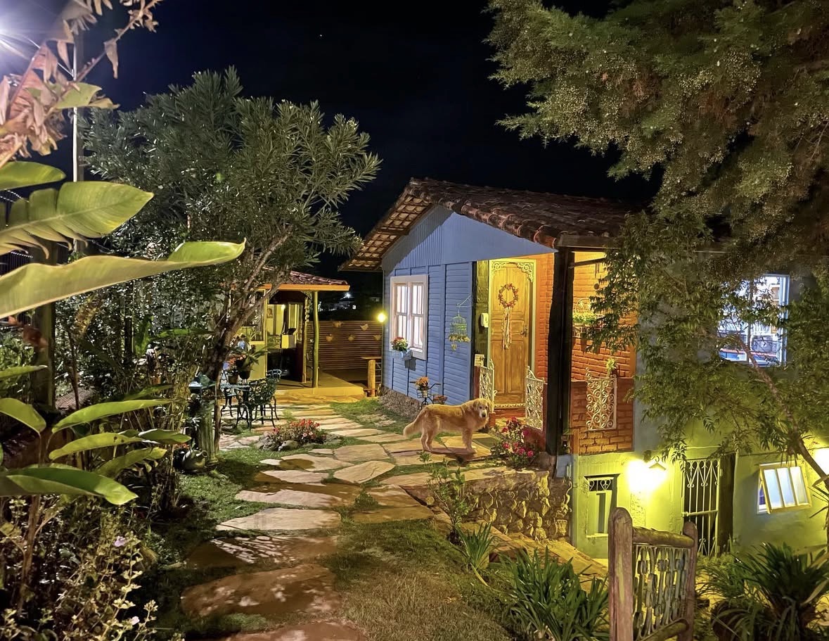 Fachada iluminada da Casa das Flores à noite, com jardim e caminho de pedra