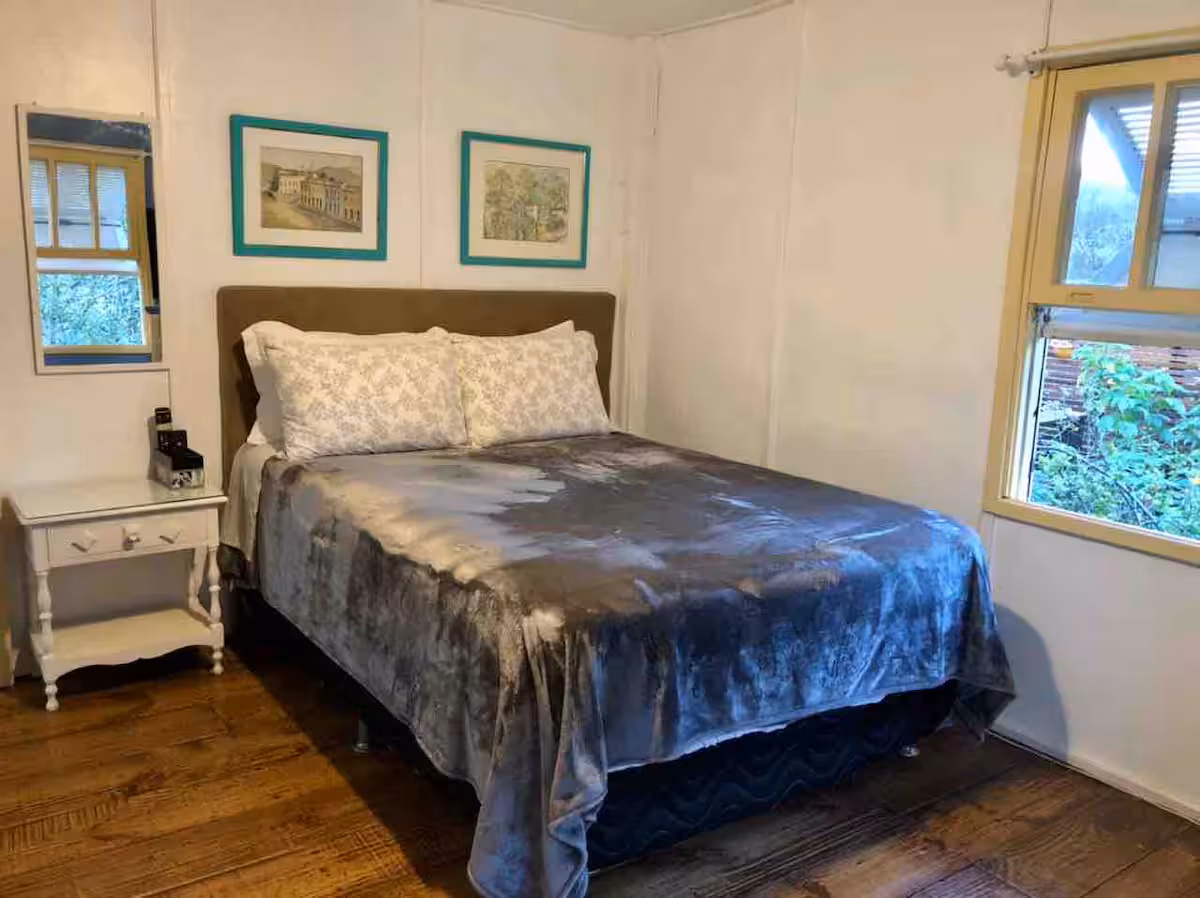 Quarto da Casa das Orquídeas com cama de casal e janela para o jardim
