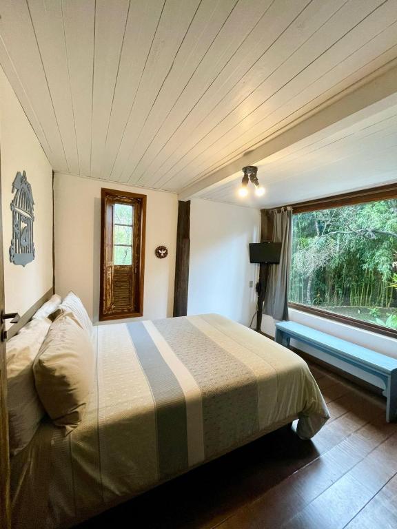 Quarto com cama de casal e janela ampla para a vegetação